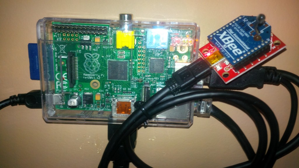 The Raspberry Pi Server velcro'd to the wall net to my desk with an XBEE connected to it via USB.  Note the XBEE is about the size of a US quarter coin.  The other connections are power on the left, HDMI monitor on the bottom, ethernet on the lower right, and a second USB under the XBEE which hooks to a USB hub that has keyboard, mouse and external hard drive!